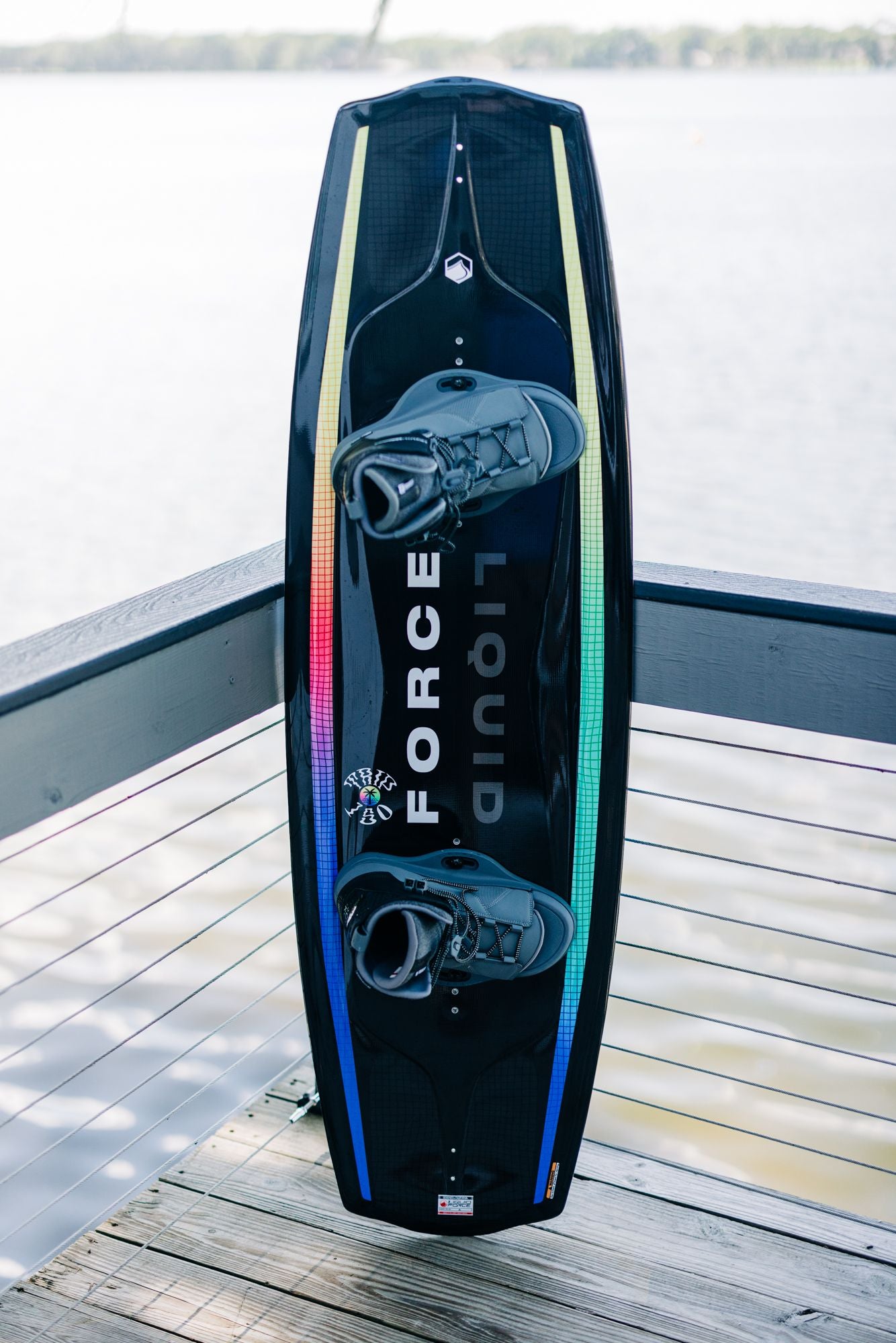 A Liquid Force 2024 Trip wakeboard, sitting on a dock next to a body of water.