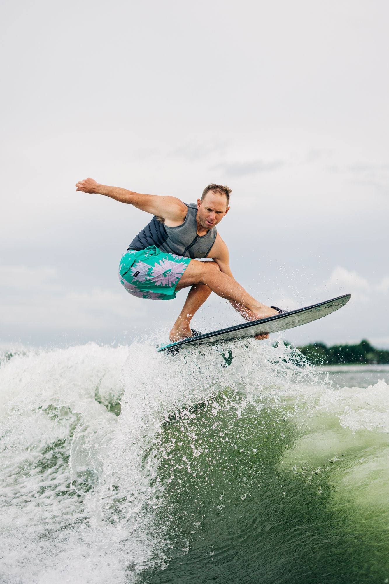 A man effortlessly rides a wave on a surfboard, utilizing the Liquid Force 2023 Primo Wakesurf Board (w/ Straps) and Dura-Surf technologies to enhance his experience.
