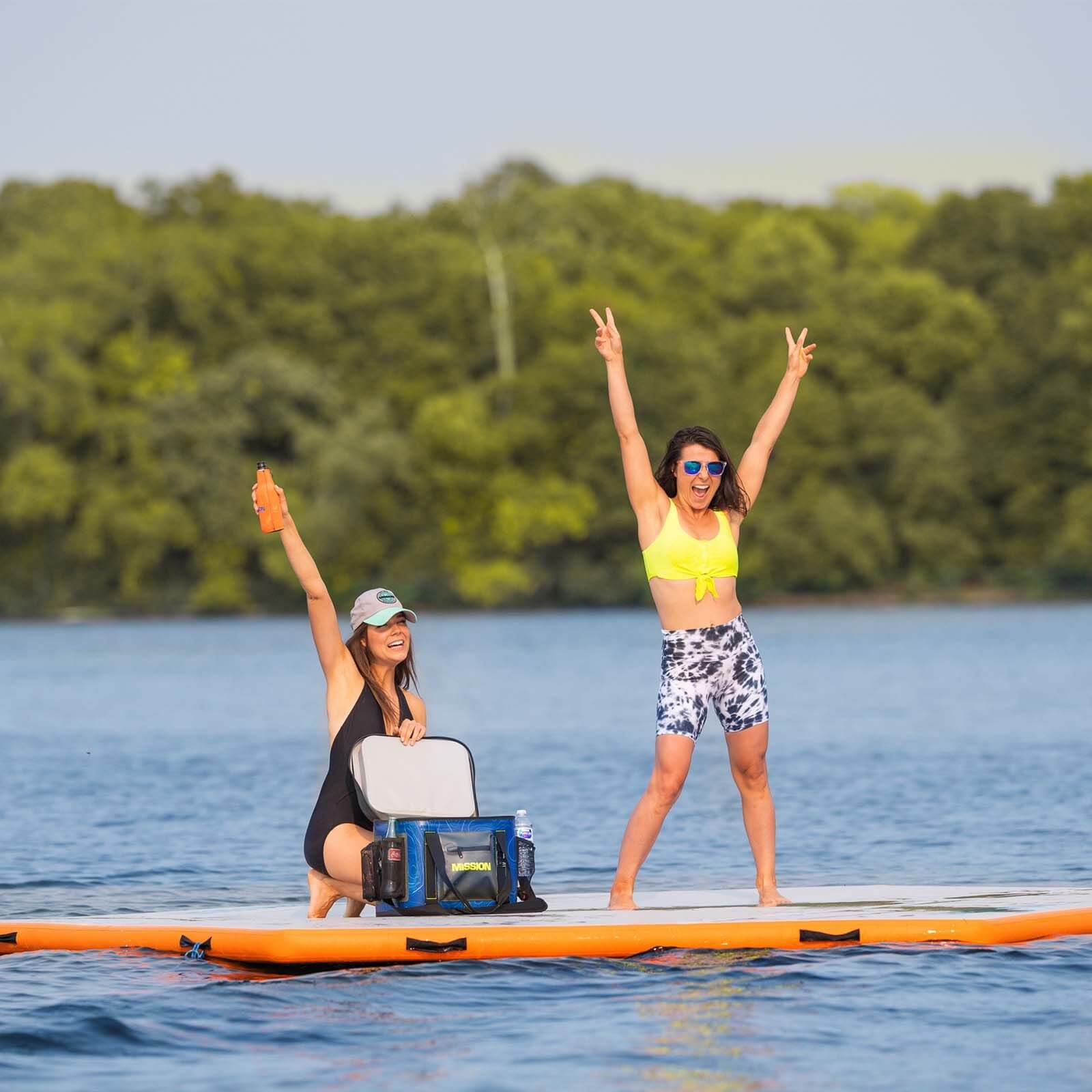 Two women enjoying a MISSION Reef Hex 112 Inflatable Water Mat-filled floating social life on an inflatable raft.