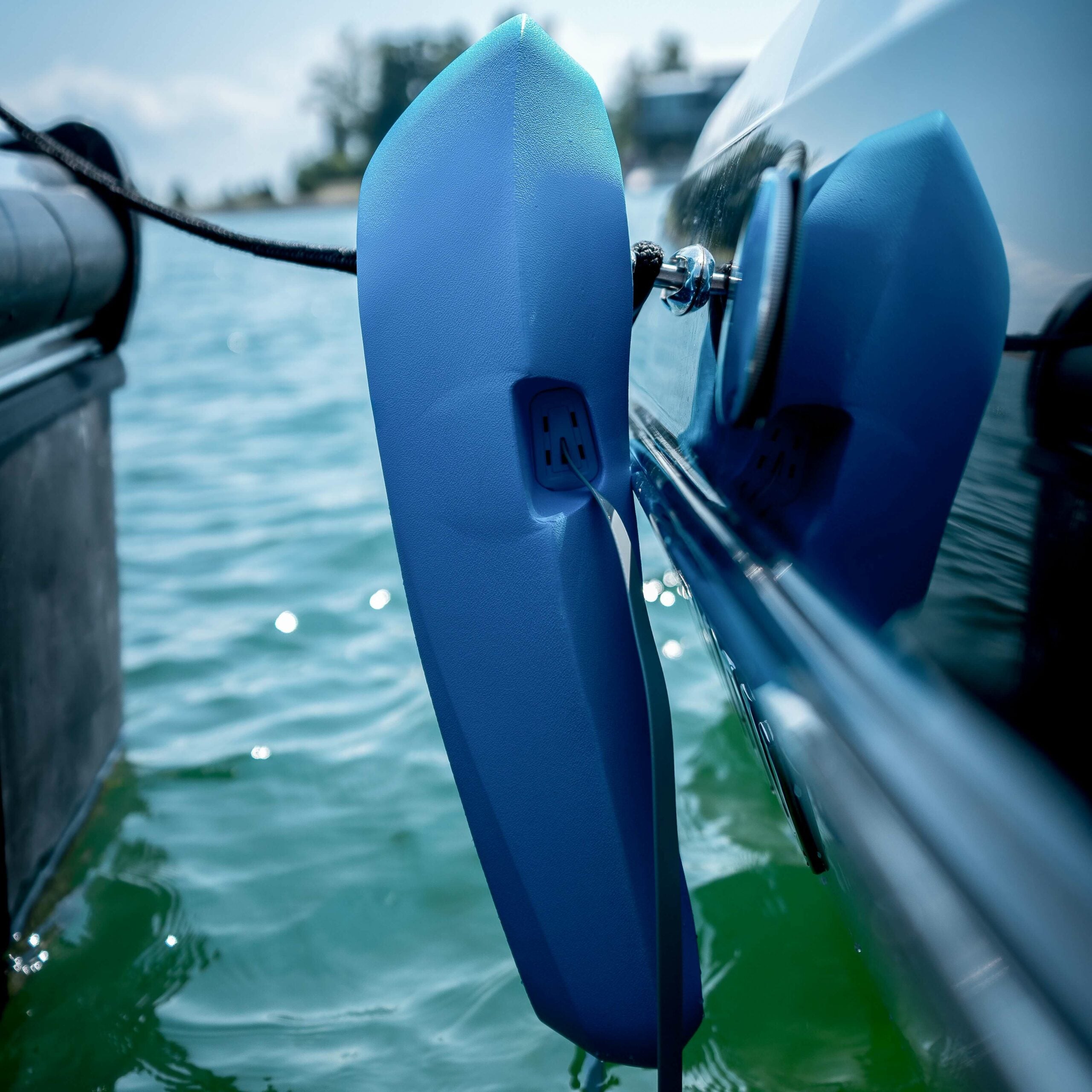 A blue boat with MISSION Sentry Boat Fenders attached to it for protection.