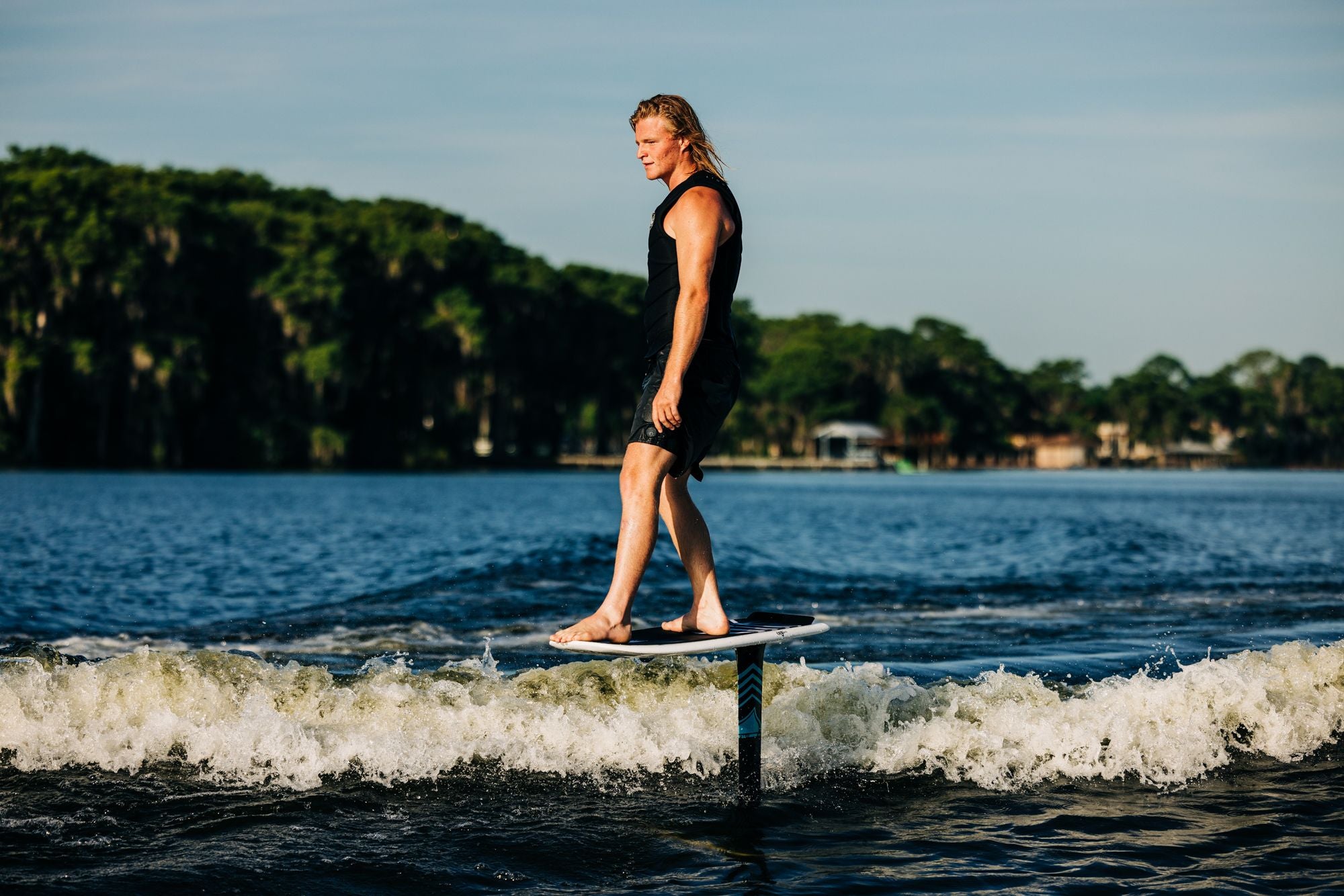 A man gracefully balancing on a Liquid Force 2024 Orb Foil Board wakeboard in the water.