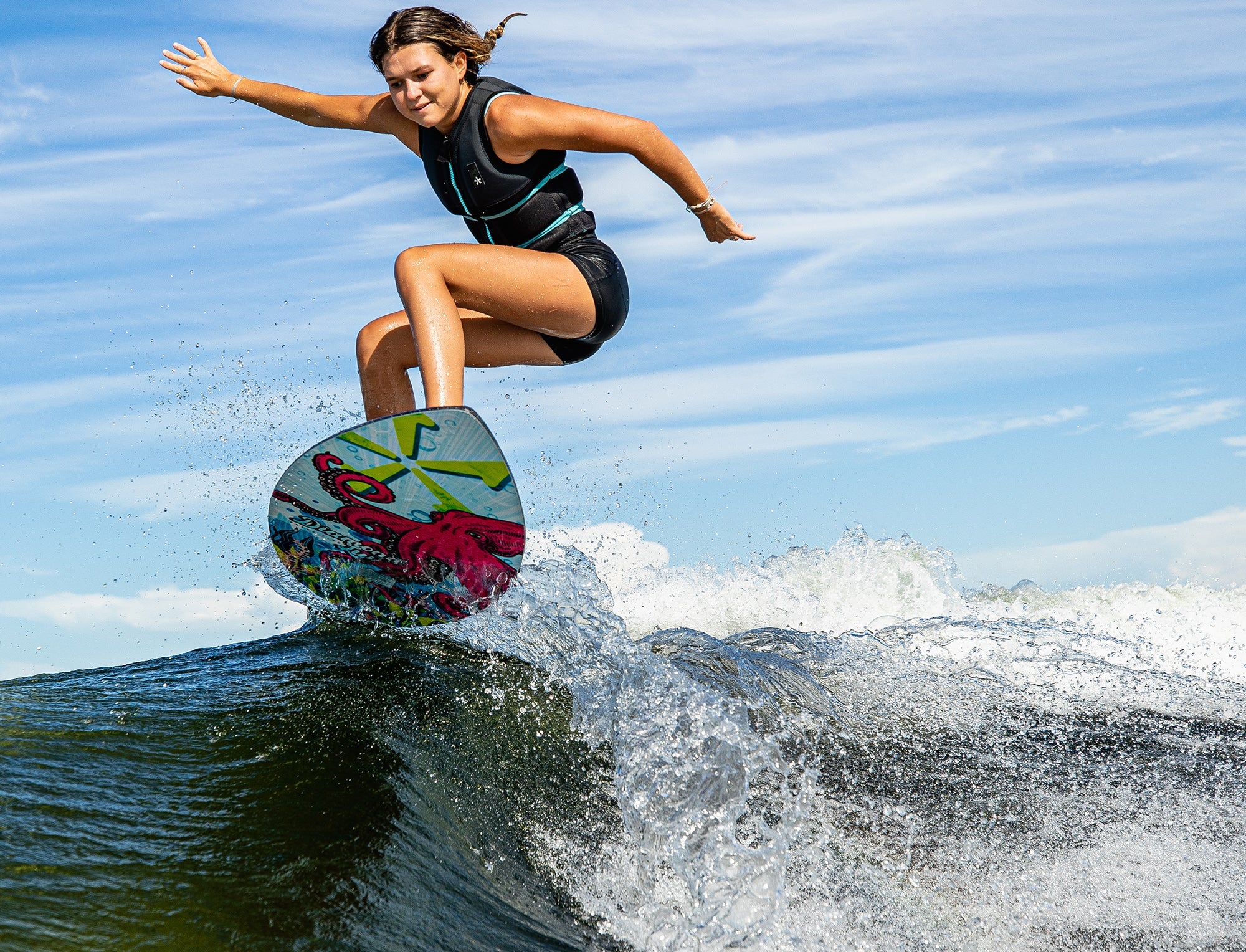 A woman is riding a wave on a Phase 5 2023 Diamond Luv Wakesurf Board.
