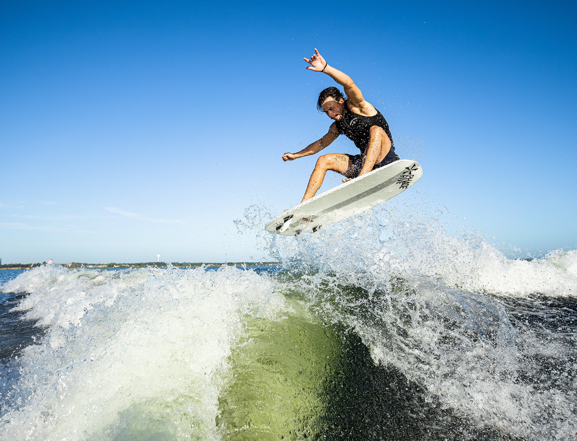A big guy surfer rides a wave on a Phase 5 2023 Doctor Wakesurf Board equipped with the FLEXTec V2 surf fin.