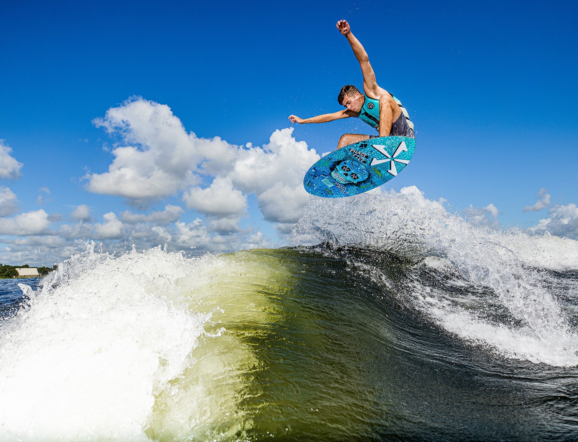 A man is riding a wave on a surfboard, showcasing his skills with the Phase 5 2023 Matrix Payne Pro Wakesurf Board. With its Matrix design and Skim Style, he effortlessly glides across the water, mastering every move.