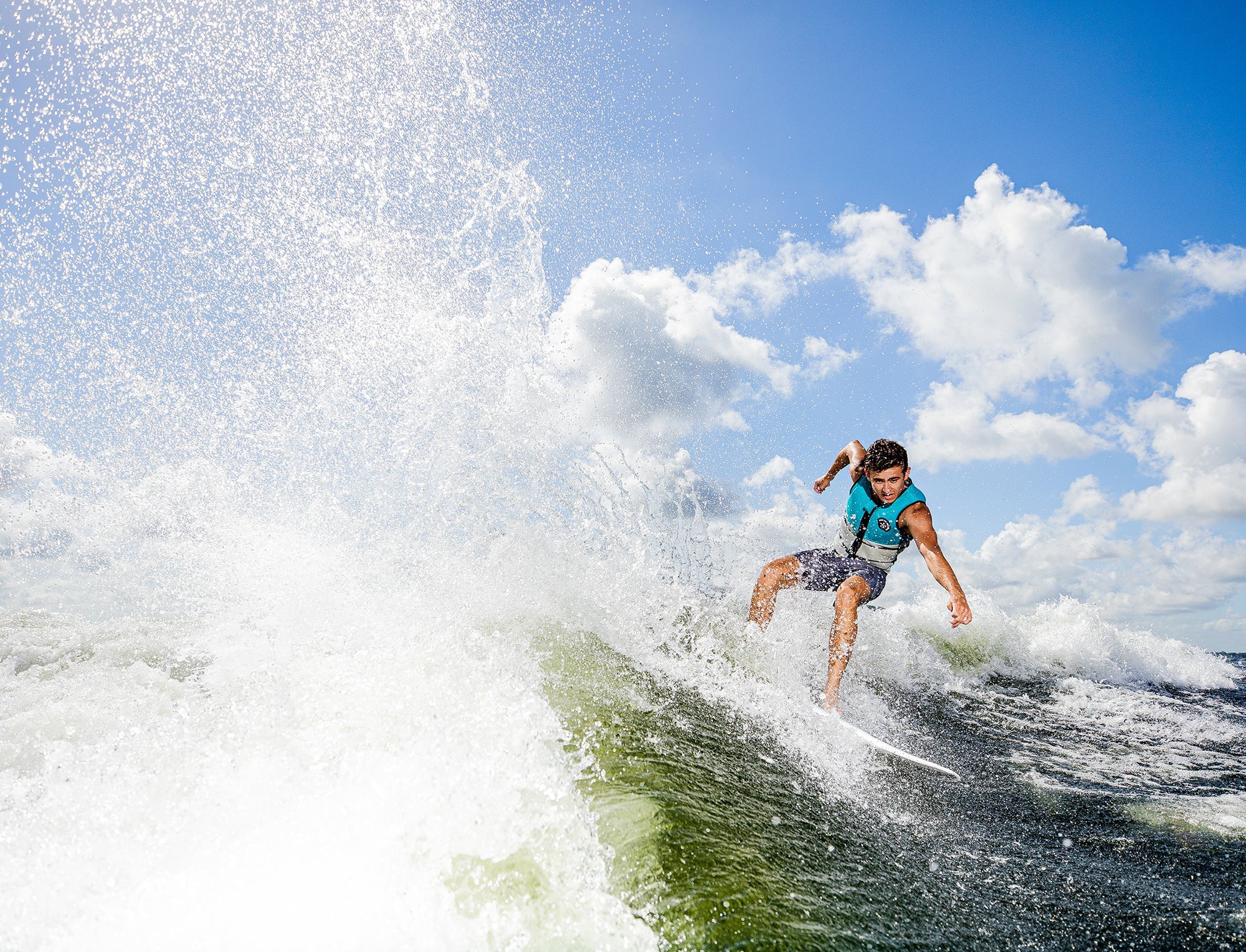 A man riding a wave on a surfboard called the Phase 5 2023 Phantom Wakesurf Board.