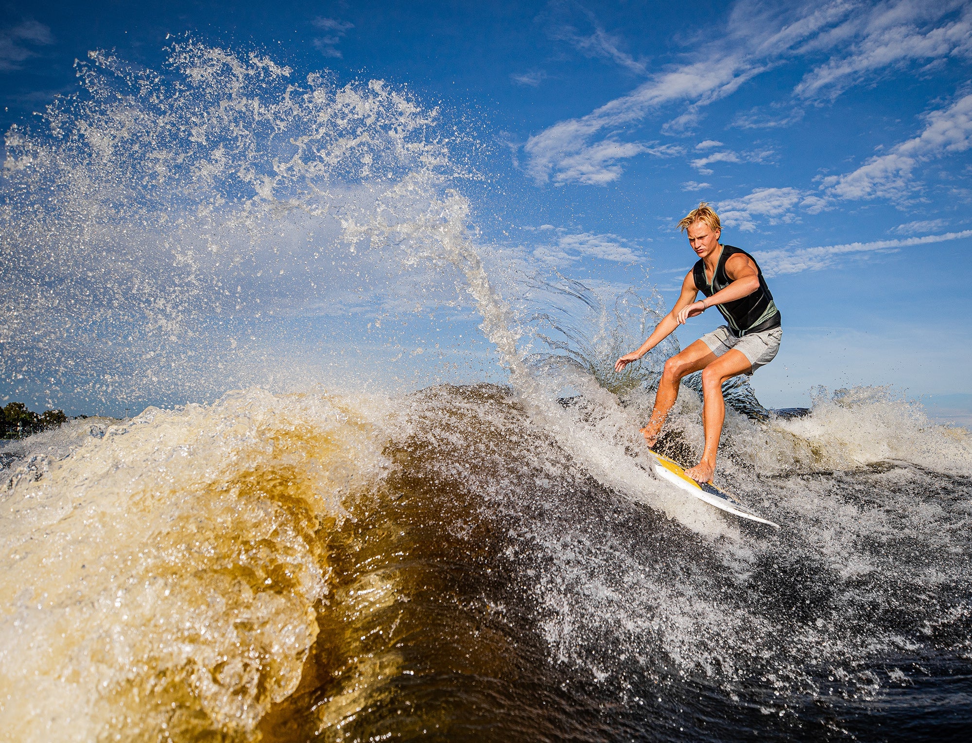 A woman riding a wave on a Phase 5 2023 Venom Wakesurf Board.
