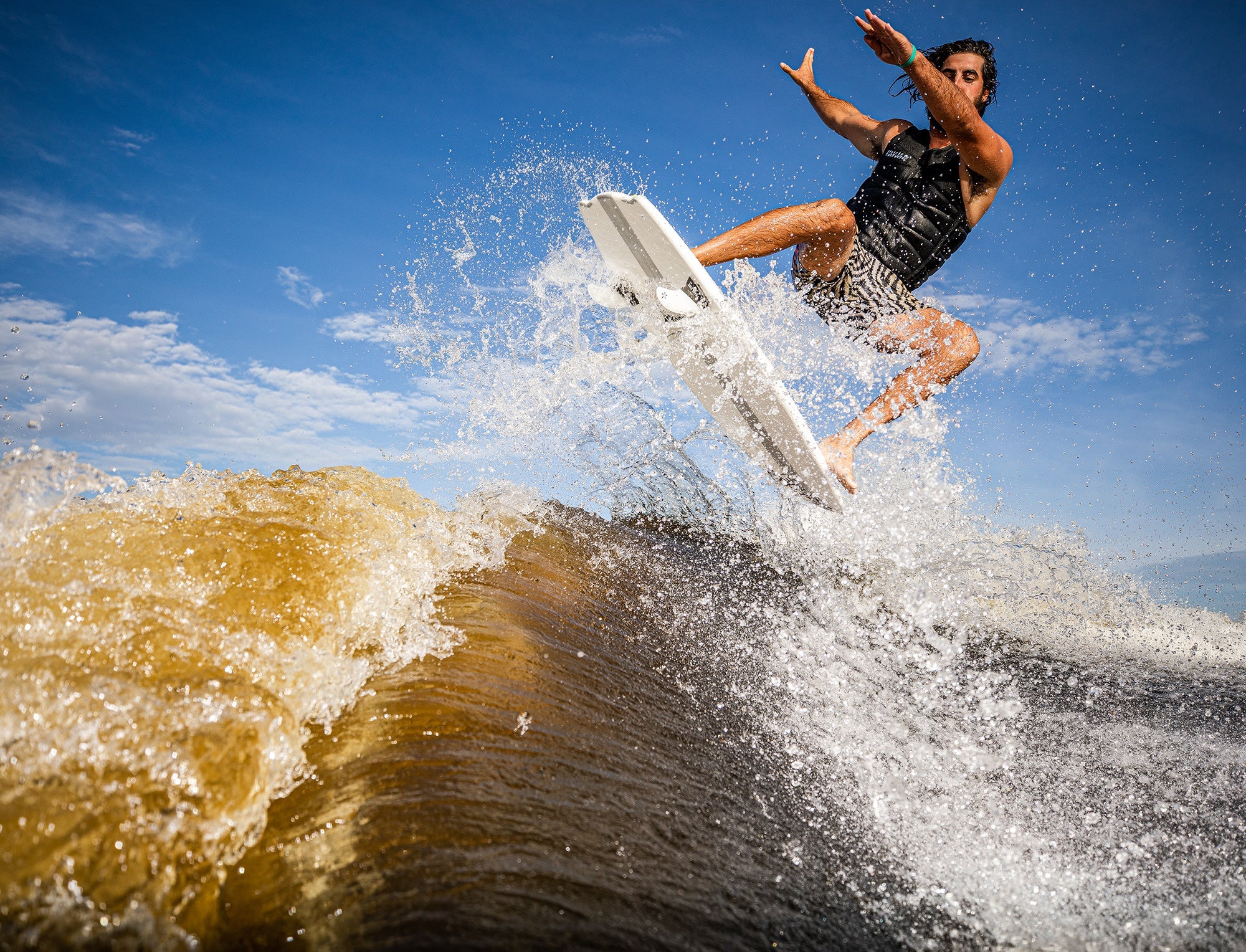 A man is riding a wave on a Phase 5 2023 Venom Wakesurf Board.