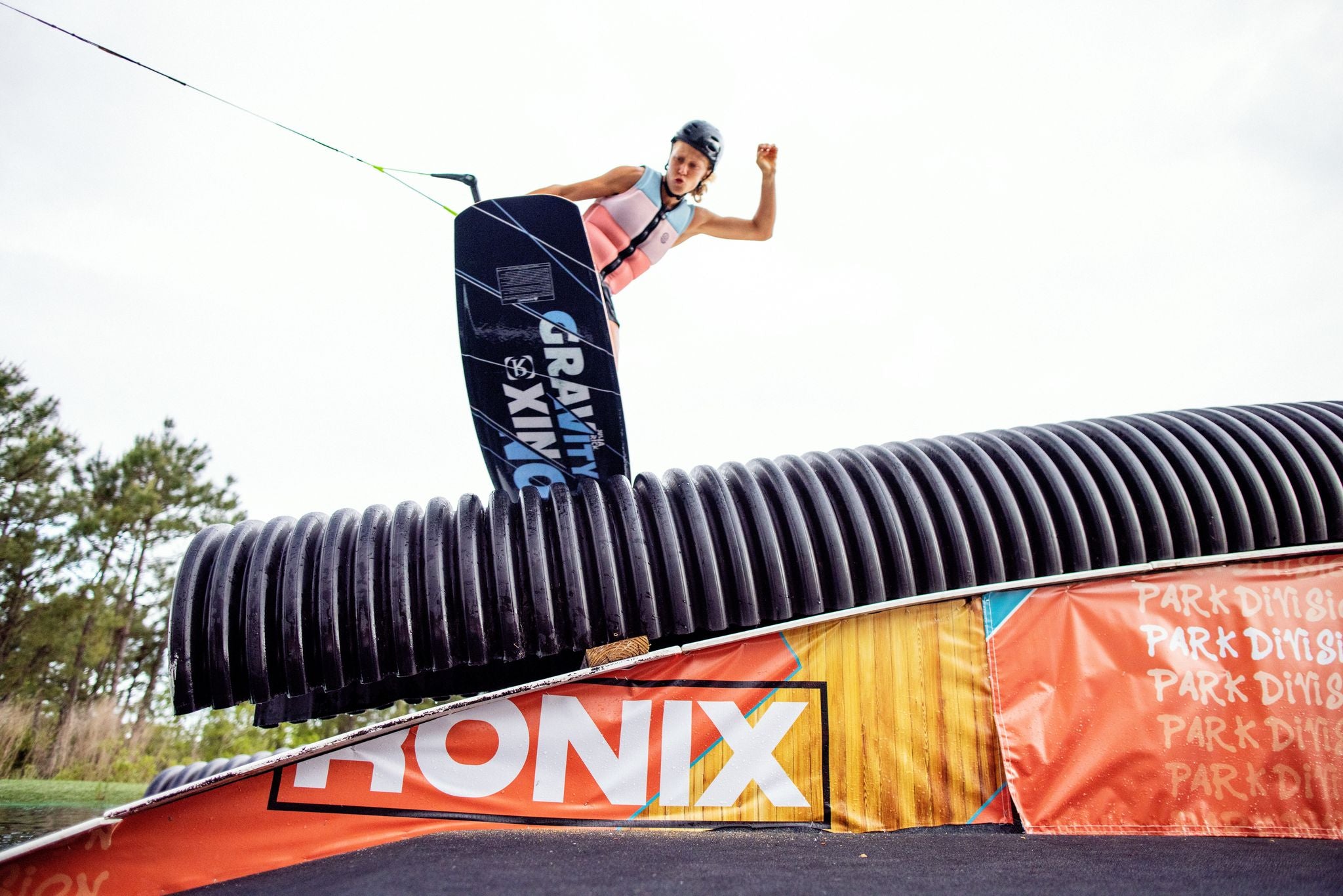 A man is riding a snowboard on a ramp while wearing a Ronix 2023 Coral Women's CE Impact Vest for added protection.