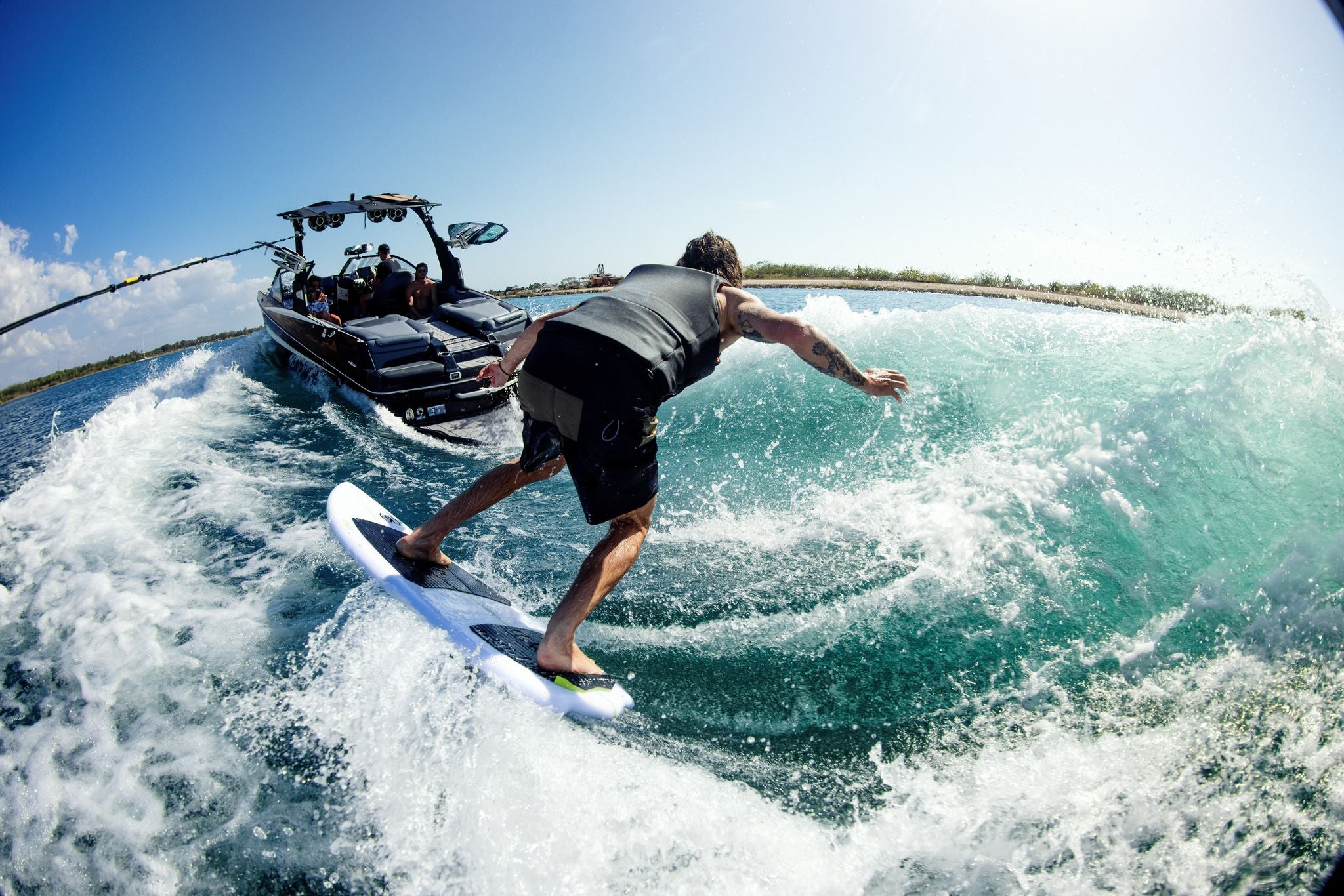 A man surfing at high speed on a Ronix 2023 Flyweight Conductor Wakesurf Board.