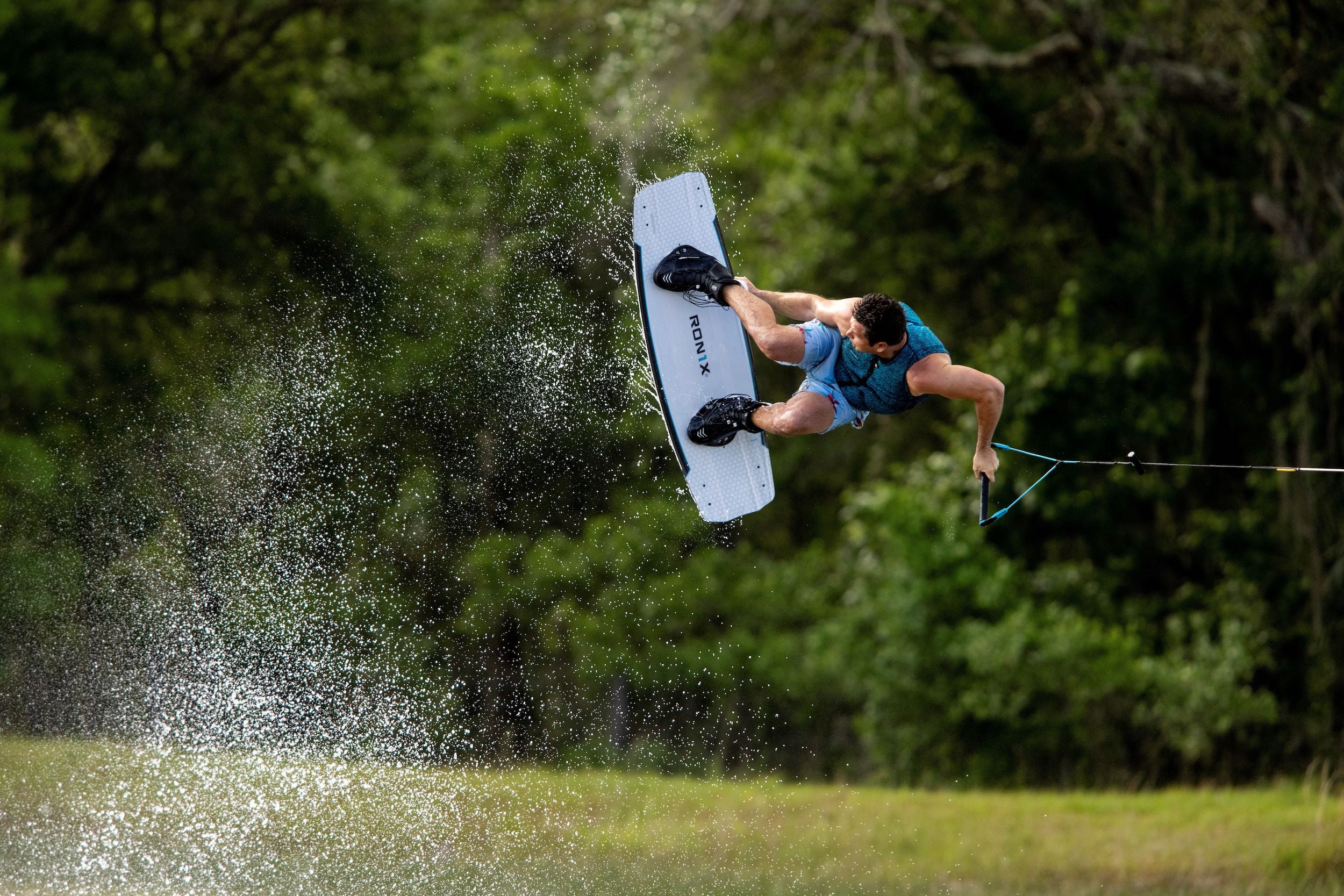 A person in the air doing a trick on a wakeboard with Ronix 2024 One Boots featuring a Cordura ballistic nylon upper and an Intuition+ heat moldable liner.