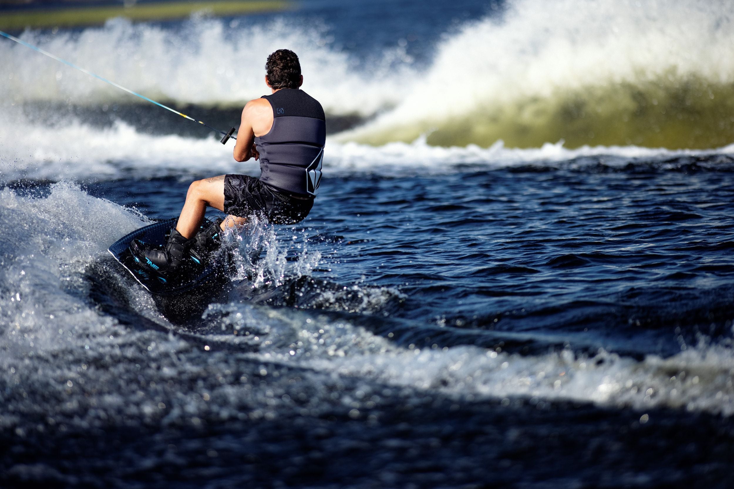 A man is water skiing on a body of water wearing Ronix 2023 One Carbitex Boots.