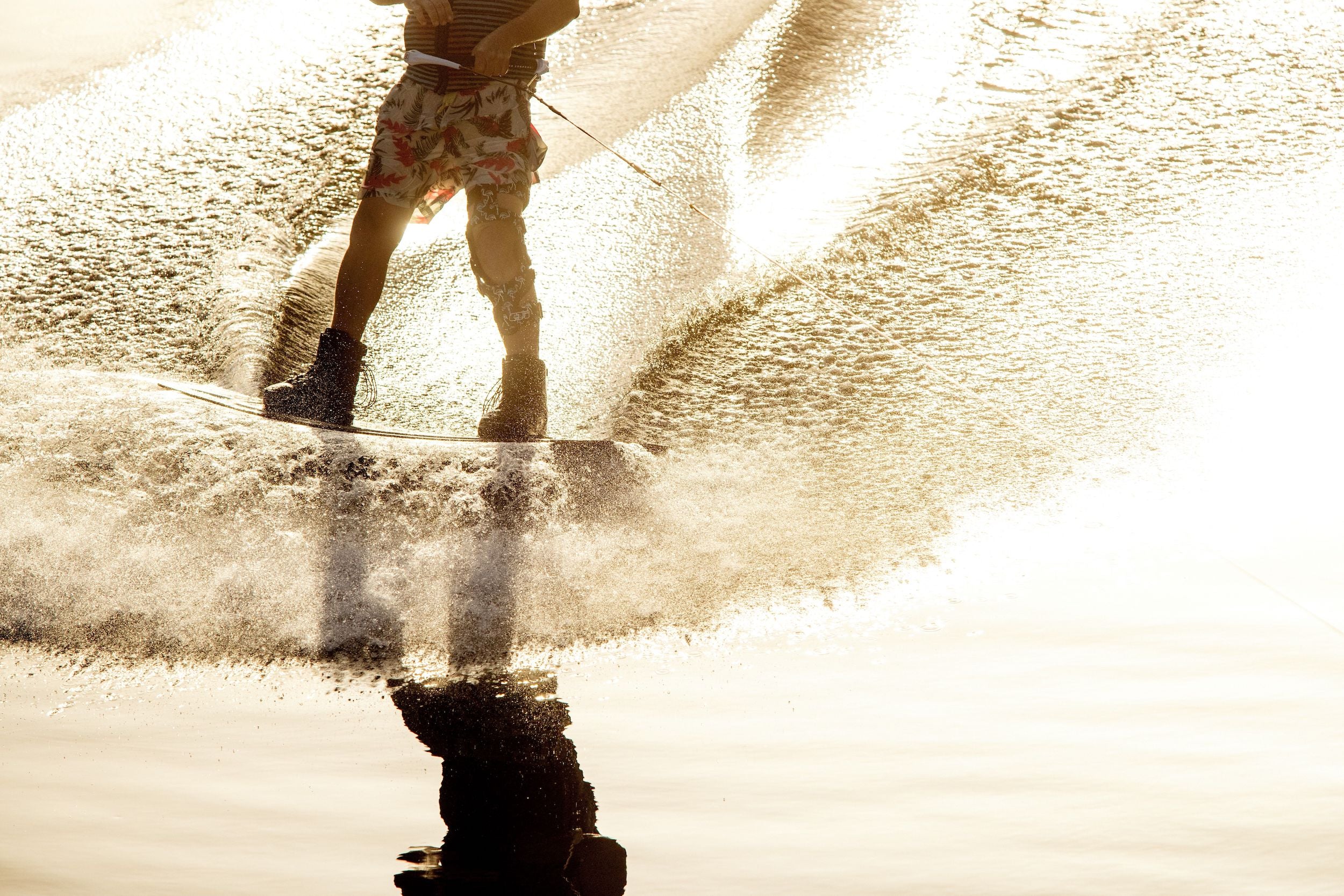 A person riding a water ski in the water, equipped with Autolock technology and using a Ronix 2024 Parks Boots.