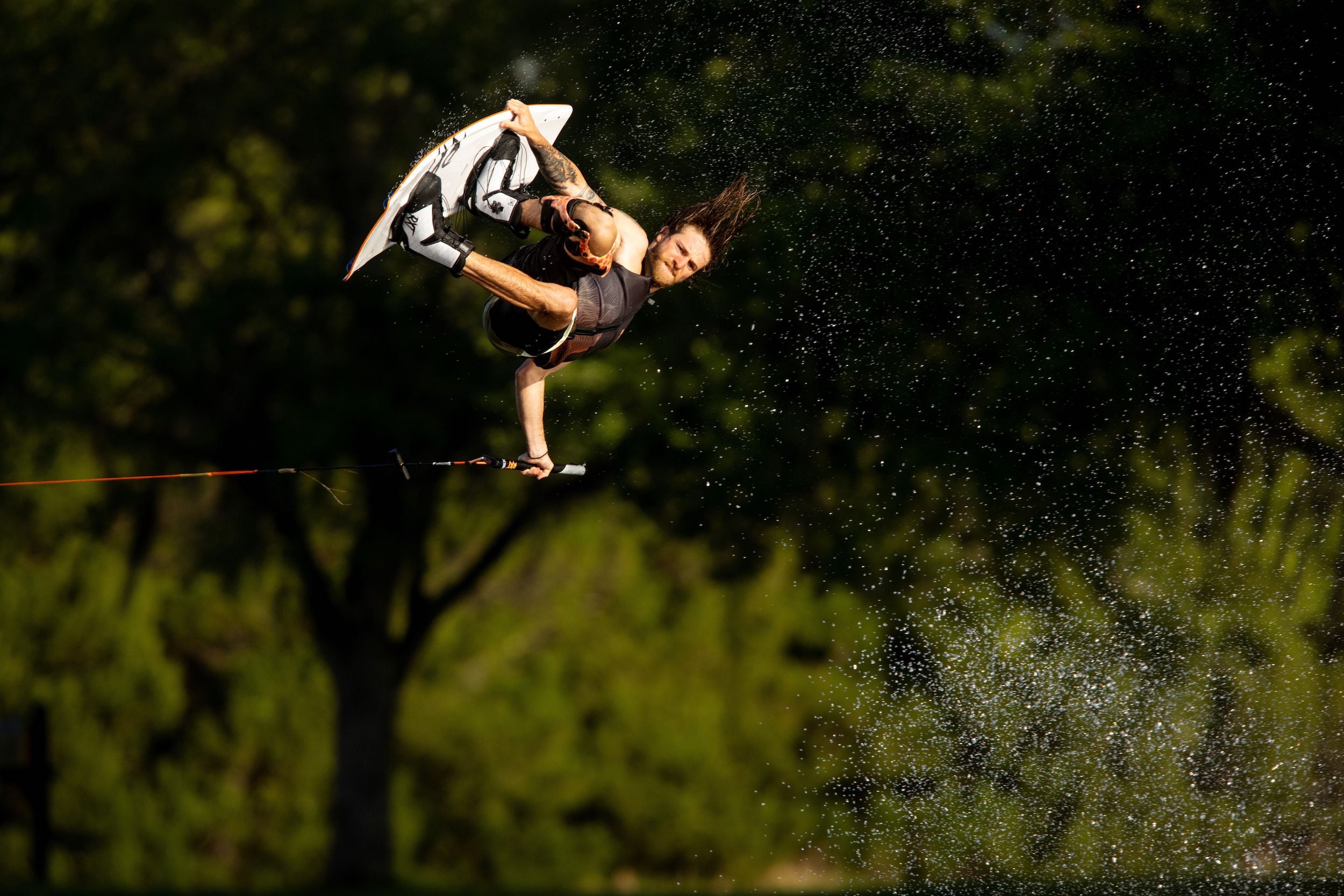 A person gliding effortlessly through the air on a wakeboard with comfortable boots and extreme lightweight flexibility, provided by the Ronix 2023 RXT Boots.