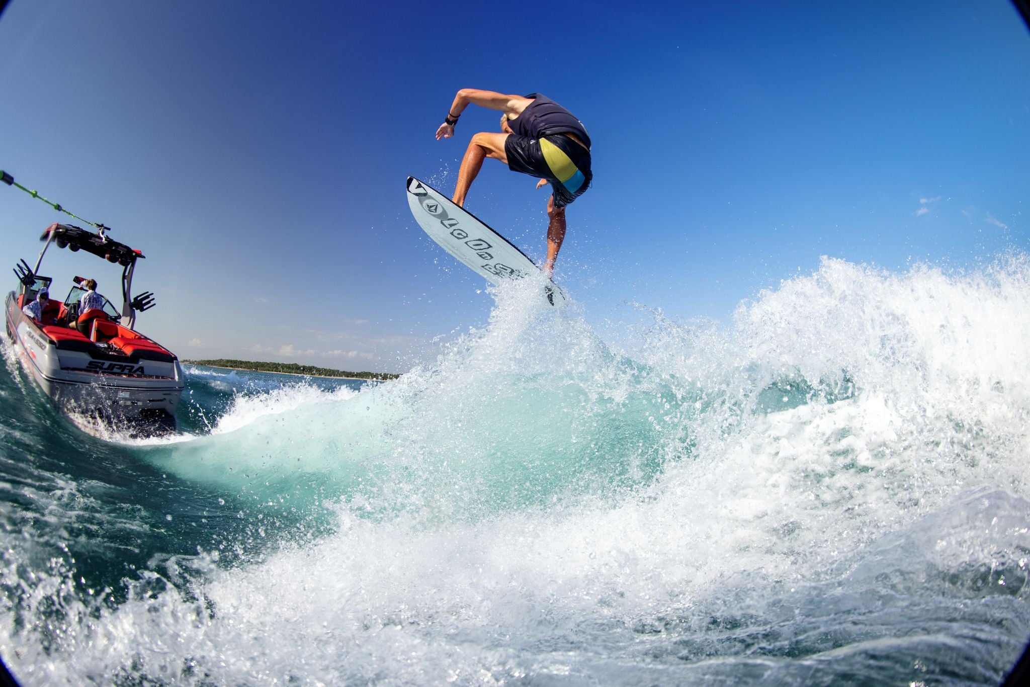 A surfer riding a Ronix 2024 Volcom Sea Captain Wakesurf Board with excellent edge hold in the water.