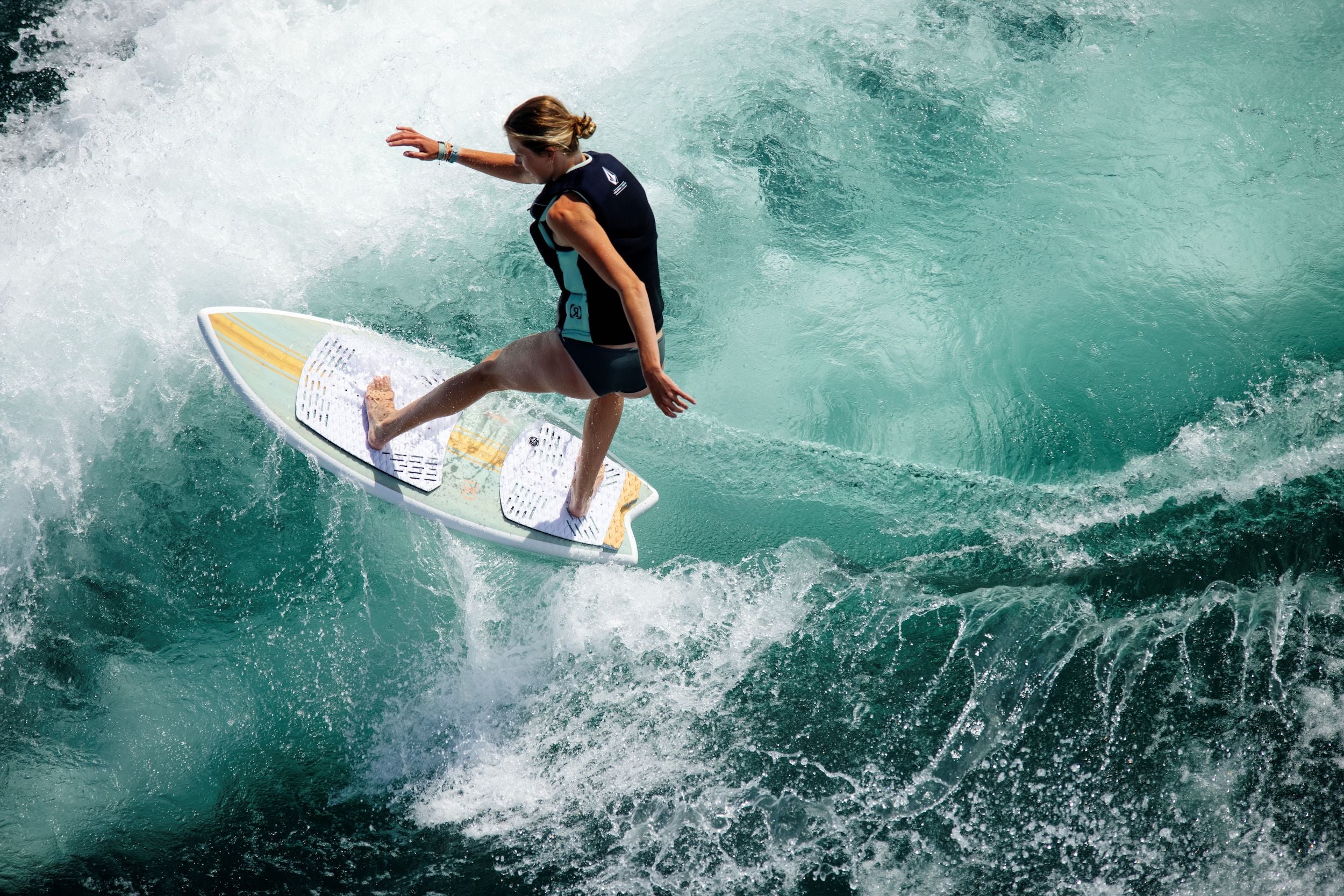 A surfer riding a wave on a Ronix 2024 Women's Koal Fish Wakesurf Board with surf style.