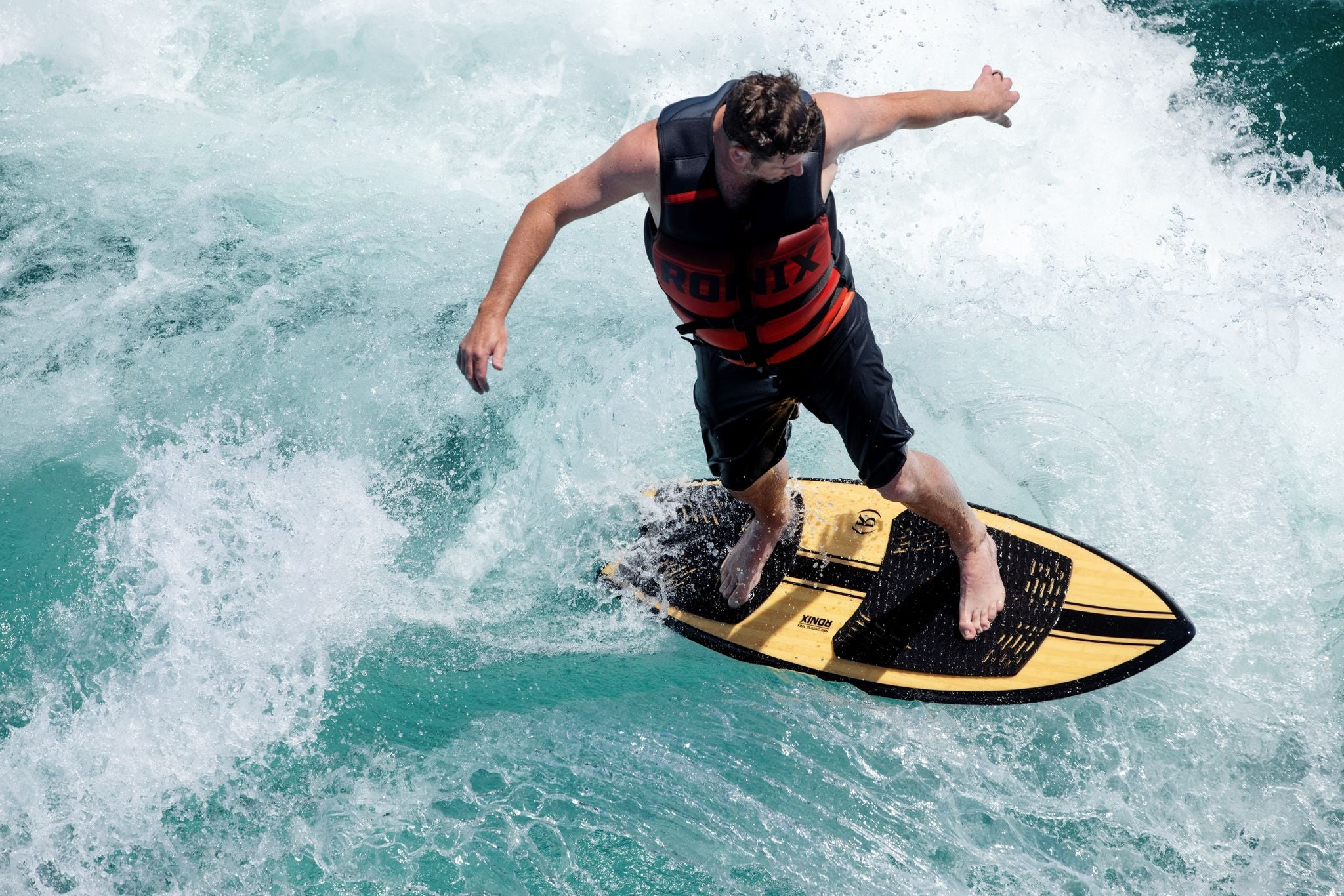 A man riding a wave on a surfboard with the Ronix Megacorp Capella 3.0 Men's CGA Vest.