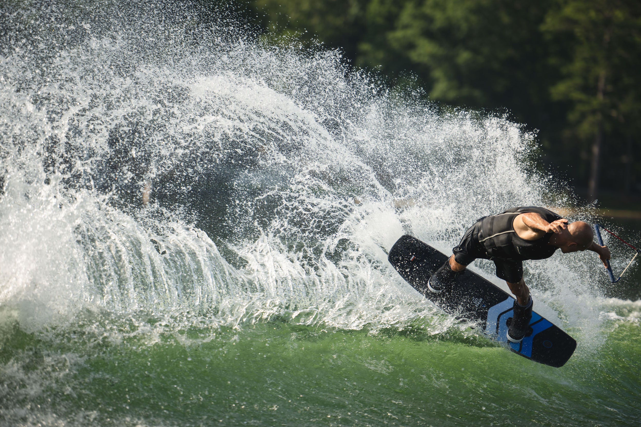 A man riding a wave on a Hyperlite 2023 Murray Pro Wakeboard with a subtle three-stage rocker.